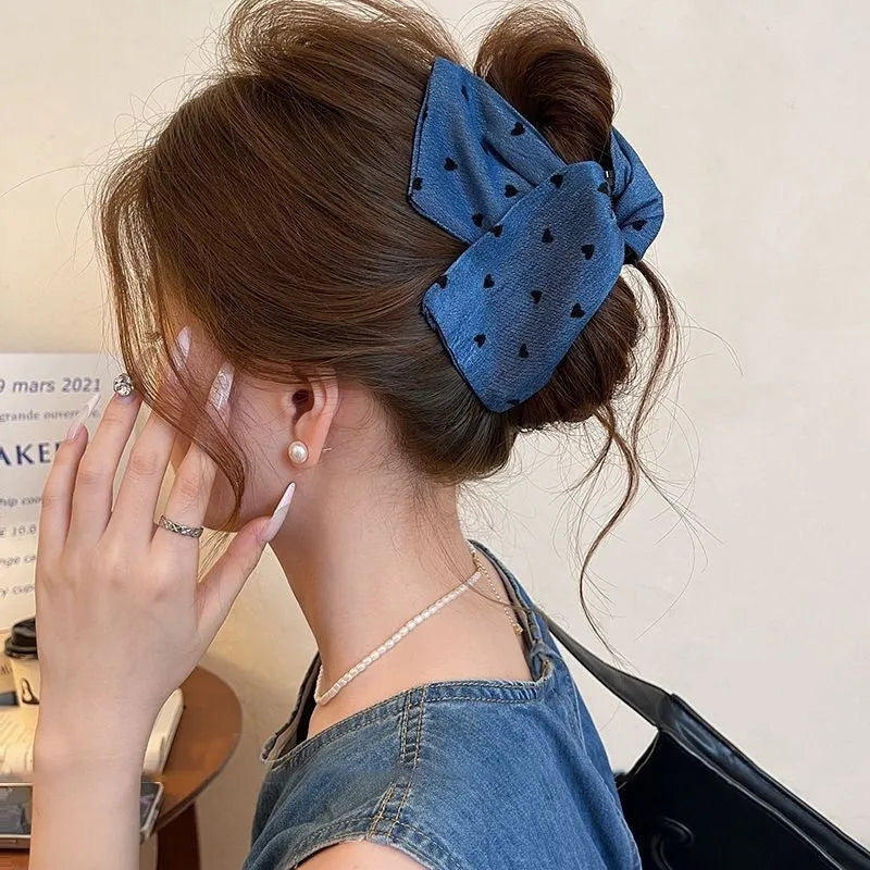 Close-up of a handmade hair clip with a denim bow and clear triangle acrylic grip.