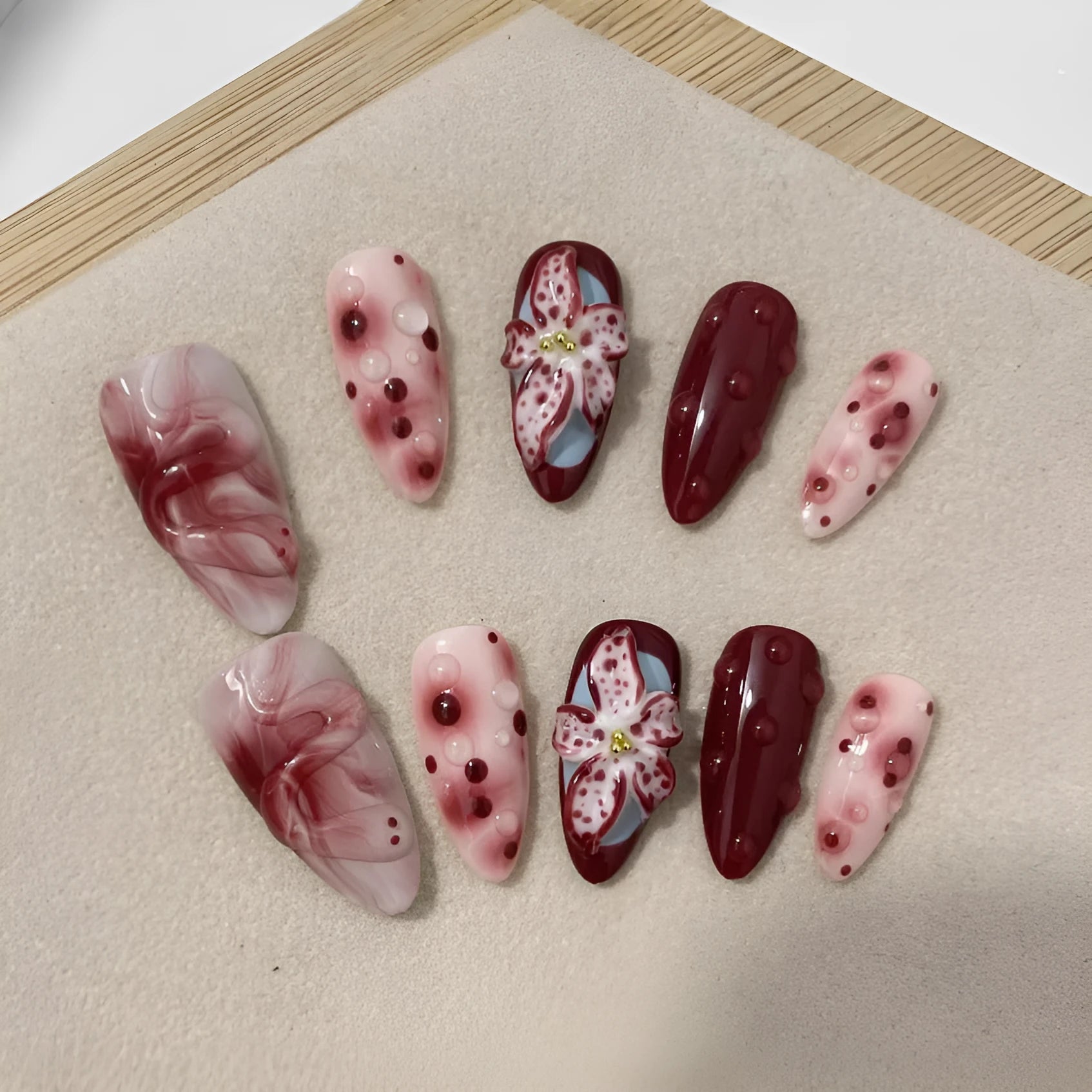Set of almond-coloured artificial nails with hand-painted rose and 3D carved butterfly designs, showing short and medium lengths.