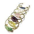 Natural rough stone crystal bracelet with gold geometric winding on a wrist.