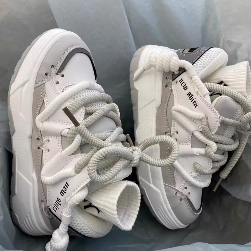 Grey retro clunky sneakers for women with thick sole for height increase and front lace-up closure.