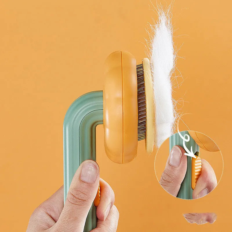Pumpkin coloured pet grooming brush with curved stainless steel needles and a hand-held plastic handle.