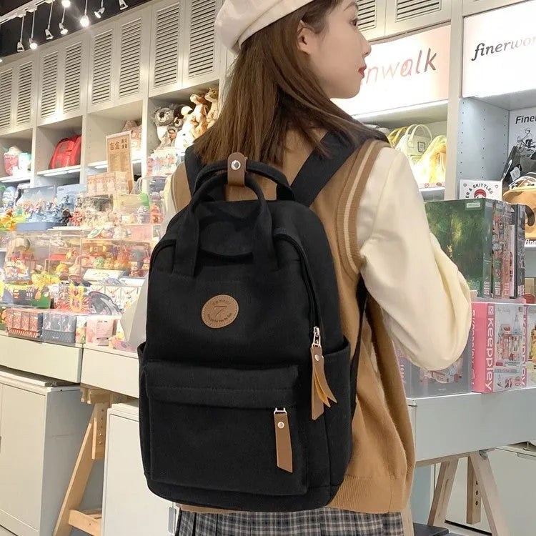 Black retro-style Oxford cloth backpack with curved shoulder straps and sewing thread detail.