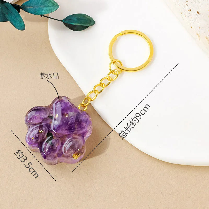 Small natural crystal cat's paw shaped pendant on a keychain ring, shown in various crystal colour options.