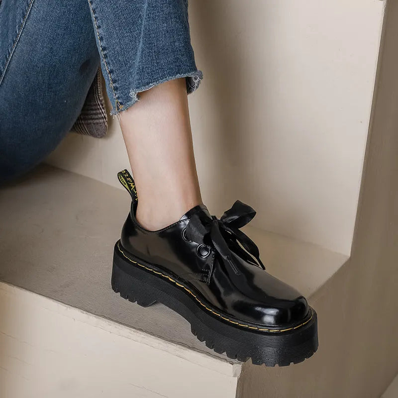 Black thick soled women's lace-up shoes with ribbon and cross strap details on superfine fibre upper
