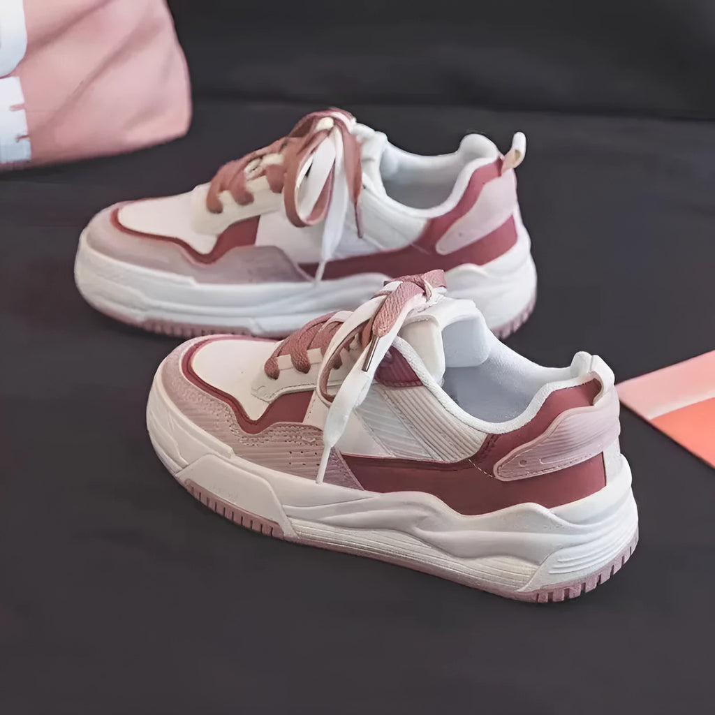 Women's pink low-top sneaker with imitation leather upper and rubber sole on a plain background.