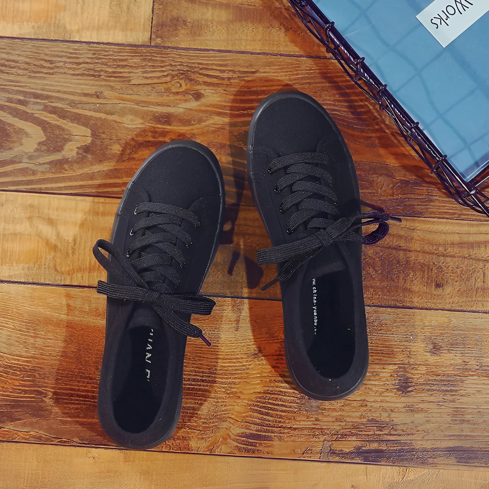 All-black women's low-top canvas shoes with lace-up front and flat rubber sole.