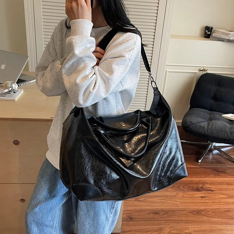 Women's hand-carrying travel bag in black or silver with 36-55L capacity
