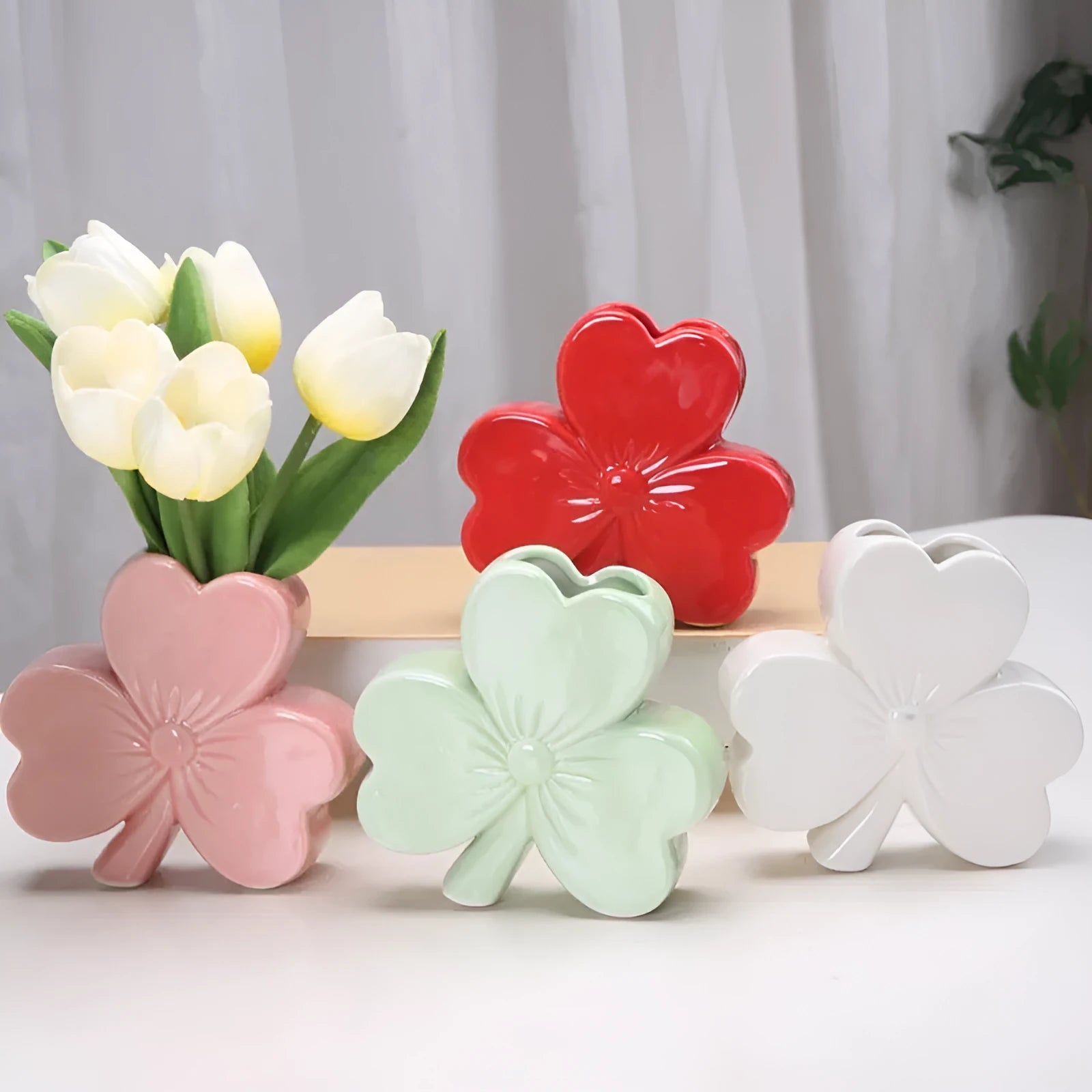 White porcelain clover-shaped ceramic vase on a desk, shown in light green colour.