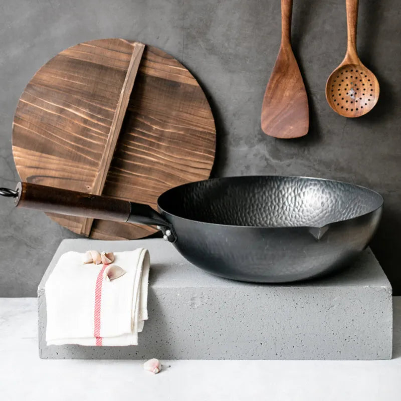 Black traditional iron wok pan with wooden handle and induction base