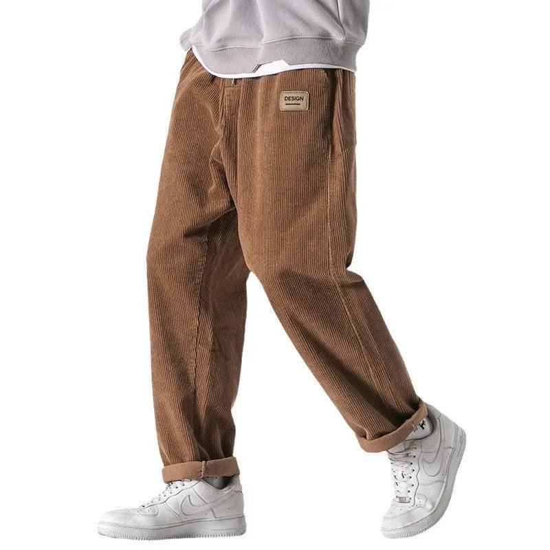 Men's loose straight corduroy sports trousers in Army Green on a grey background.