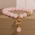 Pink crystal bracelet with a four-leaf clover pendant and rhinestone details on an alloy chain.