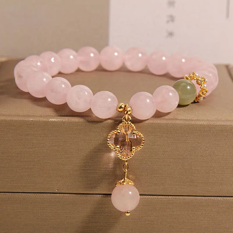 Pink crystal bracelet with a four-leaf clover pendant and rhinestone details on an alloy chain.
