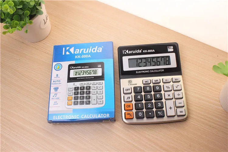 Compact silver aluminium desktop pocket calculator on a desk surface, approximate dimensions 14.5 x 11 x 2.5 cm