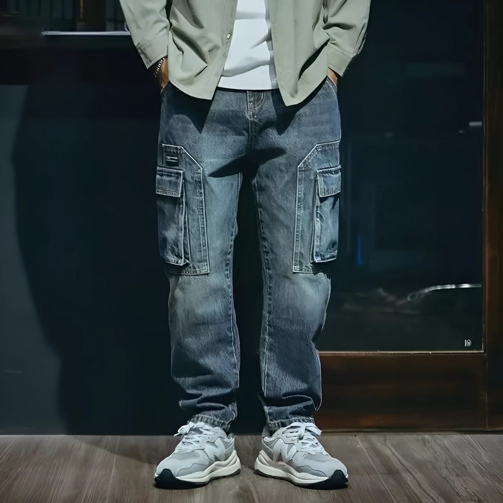 Man wearing blue loose straight-leg stretch denim trousers for a casual retro look.