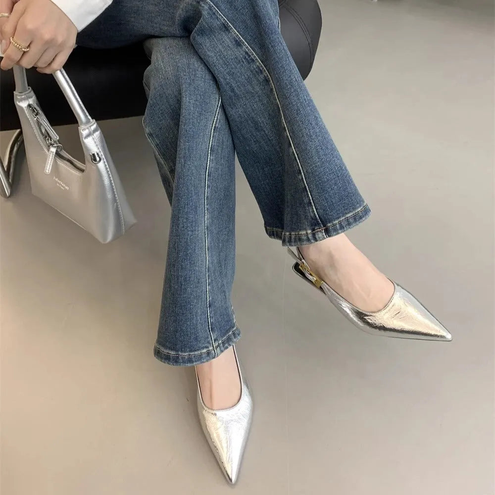 Women's black pointed leather low-heel shoes with thin decorative straps and a rubber sole.