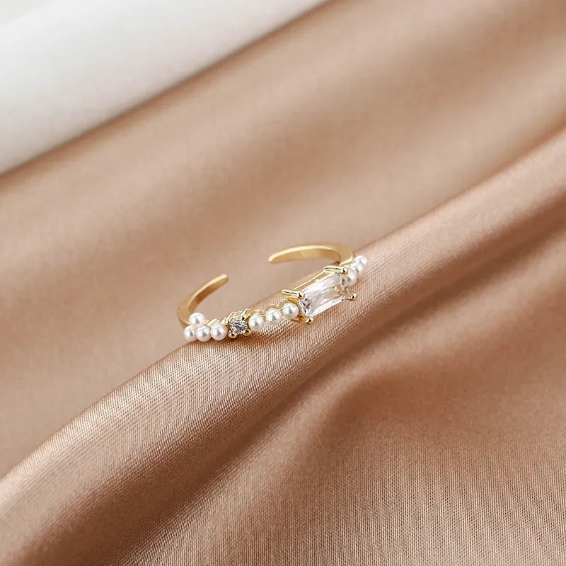 Gold alloy ring with square artificial gemstone inlay and diamond-cut surface, adjustable opening, on a white background