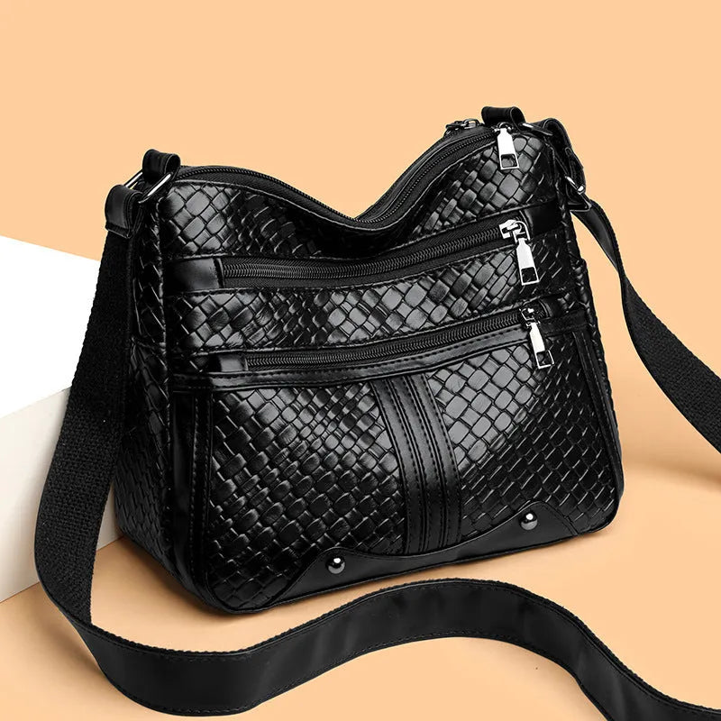Horizontal square messenger bag with multiple compartments and woven shoulder strap in black with brown trim