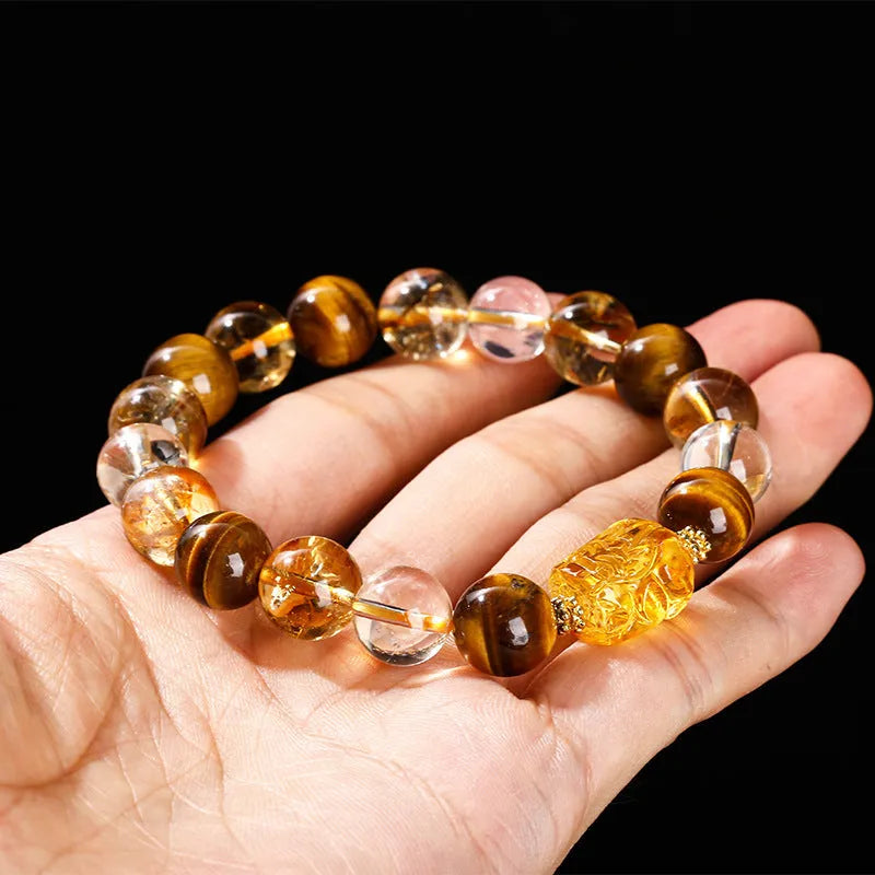 Close-up of a unisex bracelet with 10mm yellow tiger's eye and citrine round beads and a detailed beeswax pi xiu charm.