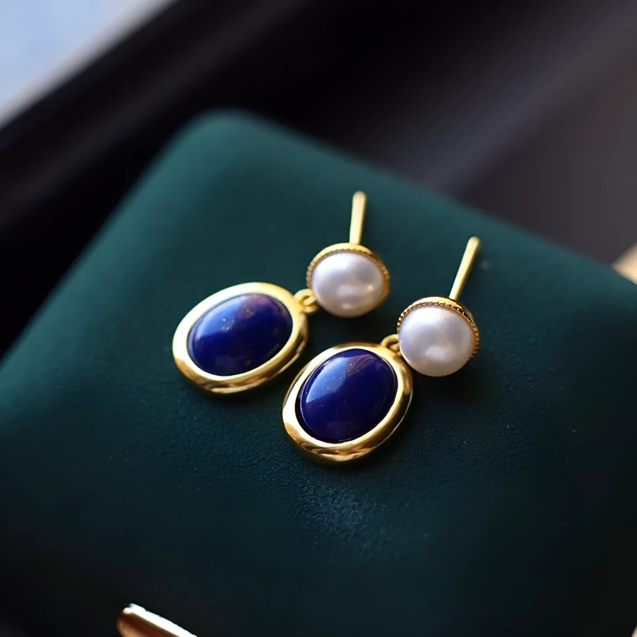 A pair of simple sterling silver drop earrings with blue lapis lazuli pearls and an auspicious pattern.