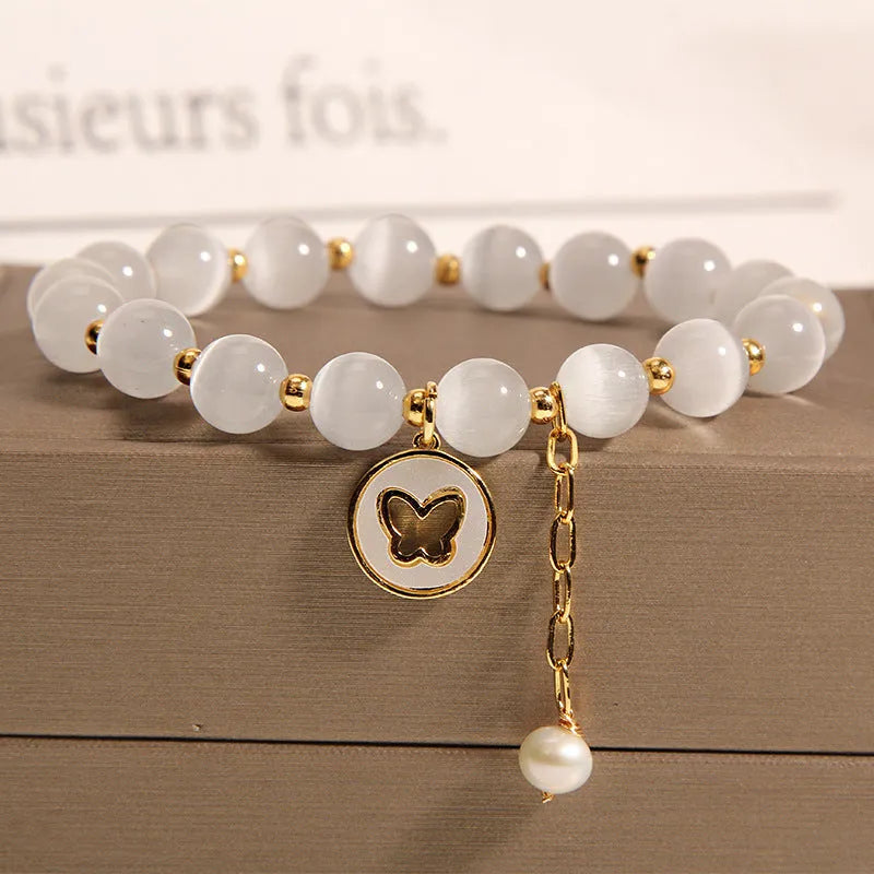 Close-up of a white cat's eye crystal bracelet with geometric links on a wrist.