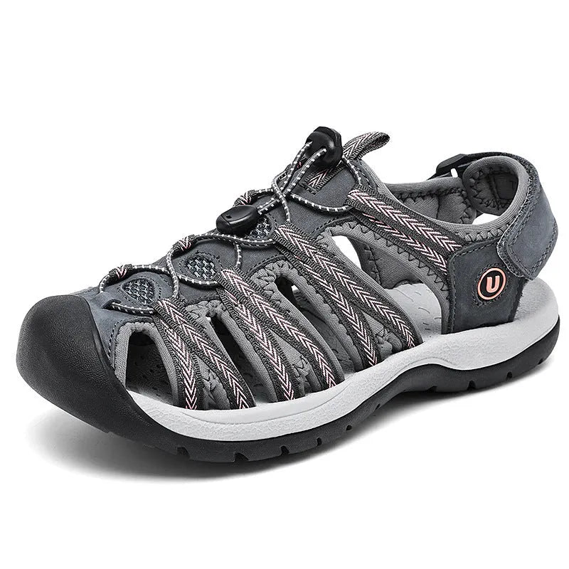 Women's black leather mesh toe box sandals with elastic band and rubber sole on a beach