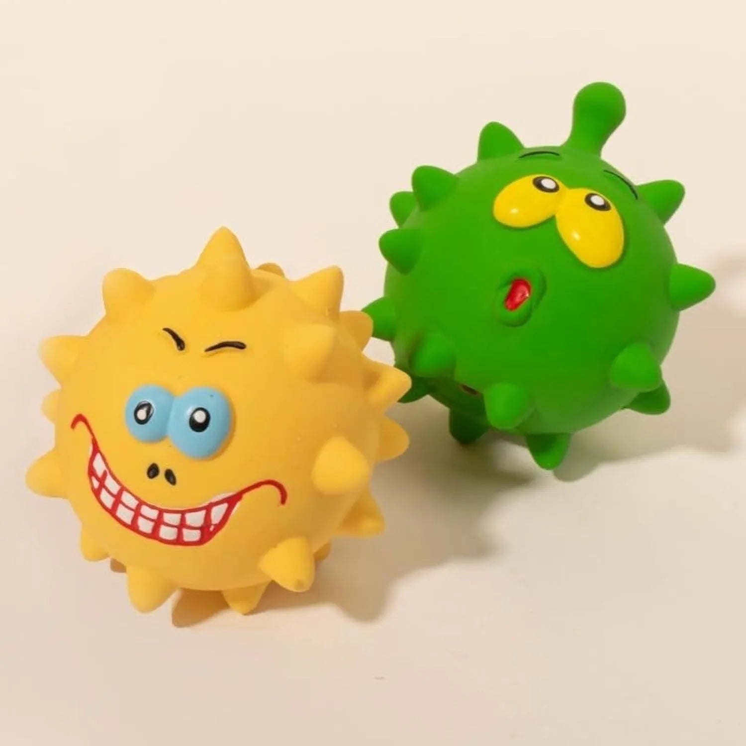 Set of four coloured latex squeaky dog balls with cute faces, shown next to a dog.