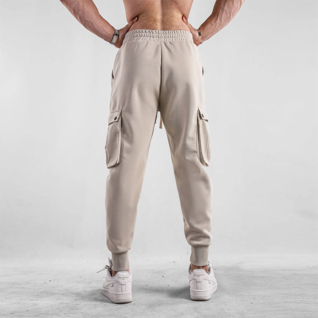 Man wearing loose light grey cotton sports trousers with ankle ties and multiple pockets.