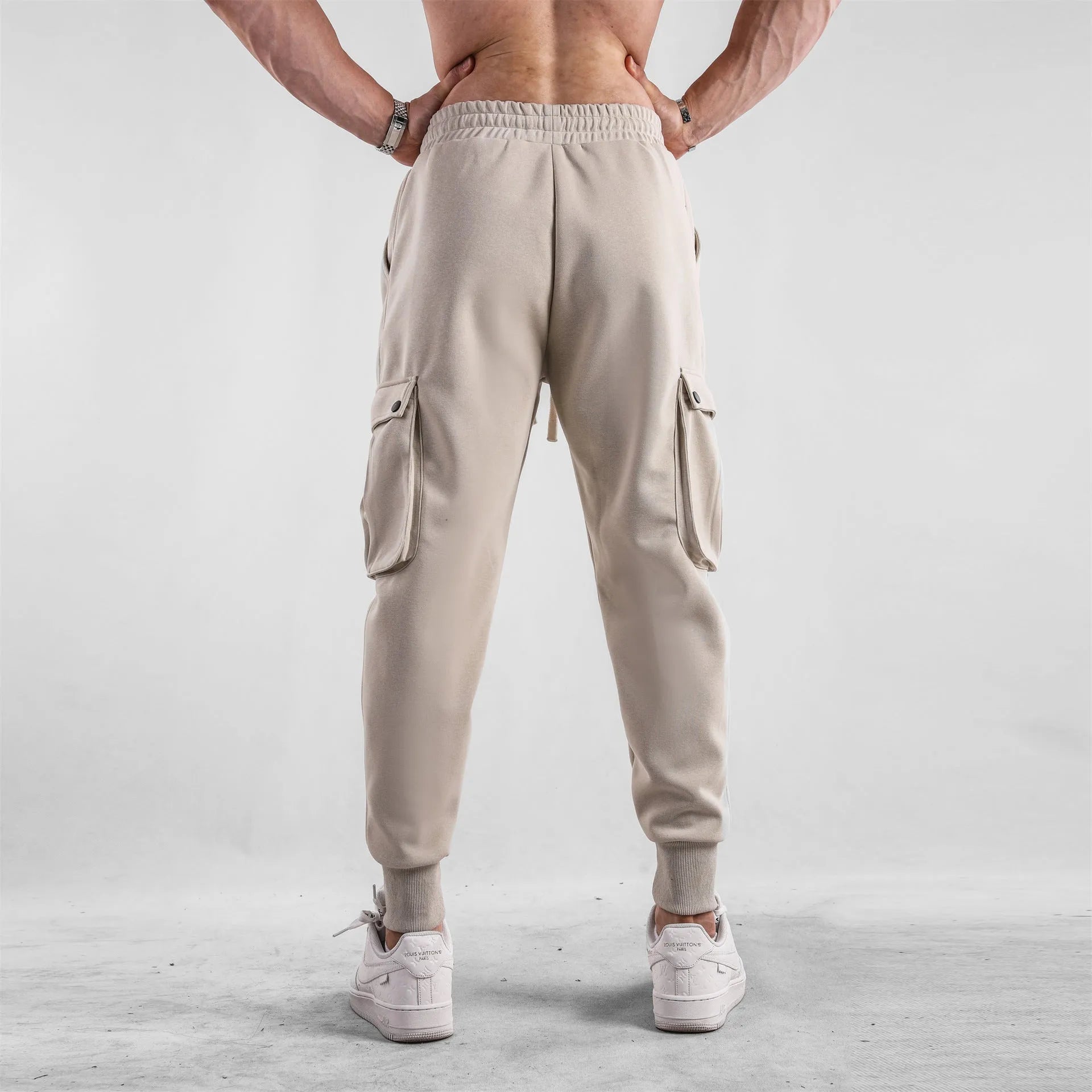 Man wearing loose light grey cotton sports trousers with ankle ties and multiple pockets.