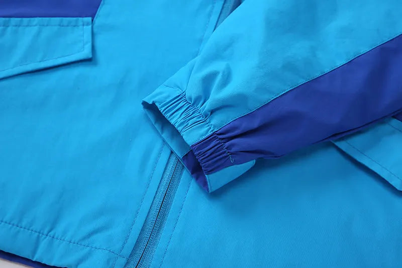 Blue lightweight boys' jacket with long sleeves and a zip, shown on a hanger.