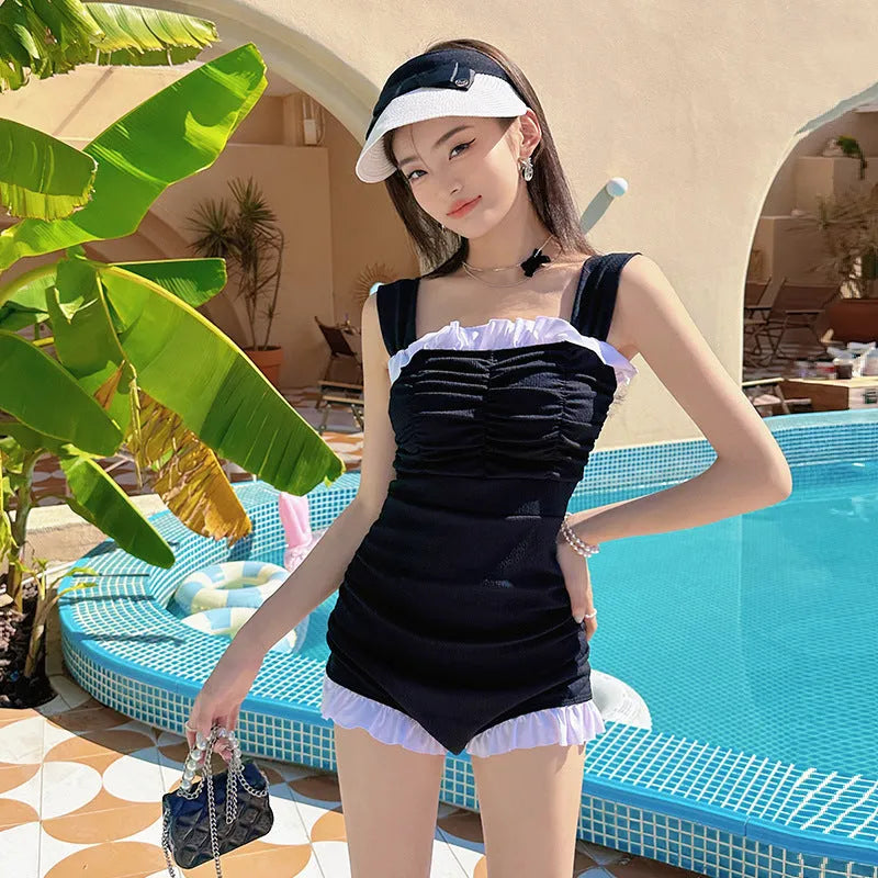 Women's solid colour one-piece swimsuit with suspender straps in black, pink, or green.