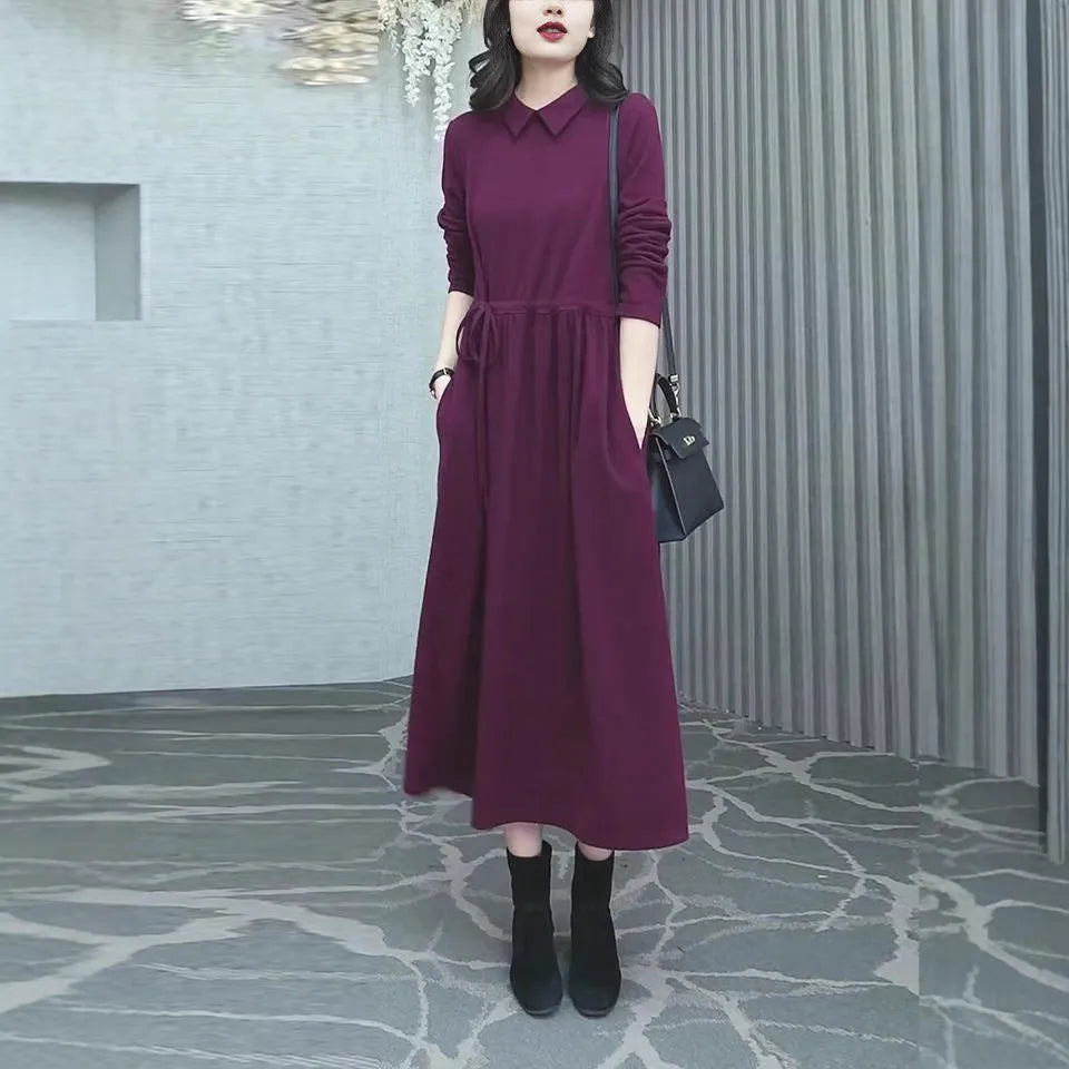 A purplish red plus size long sleeve dress with an ankle-length skirt on a mannequin.