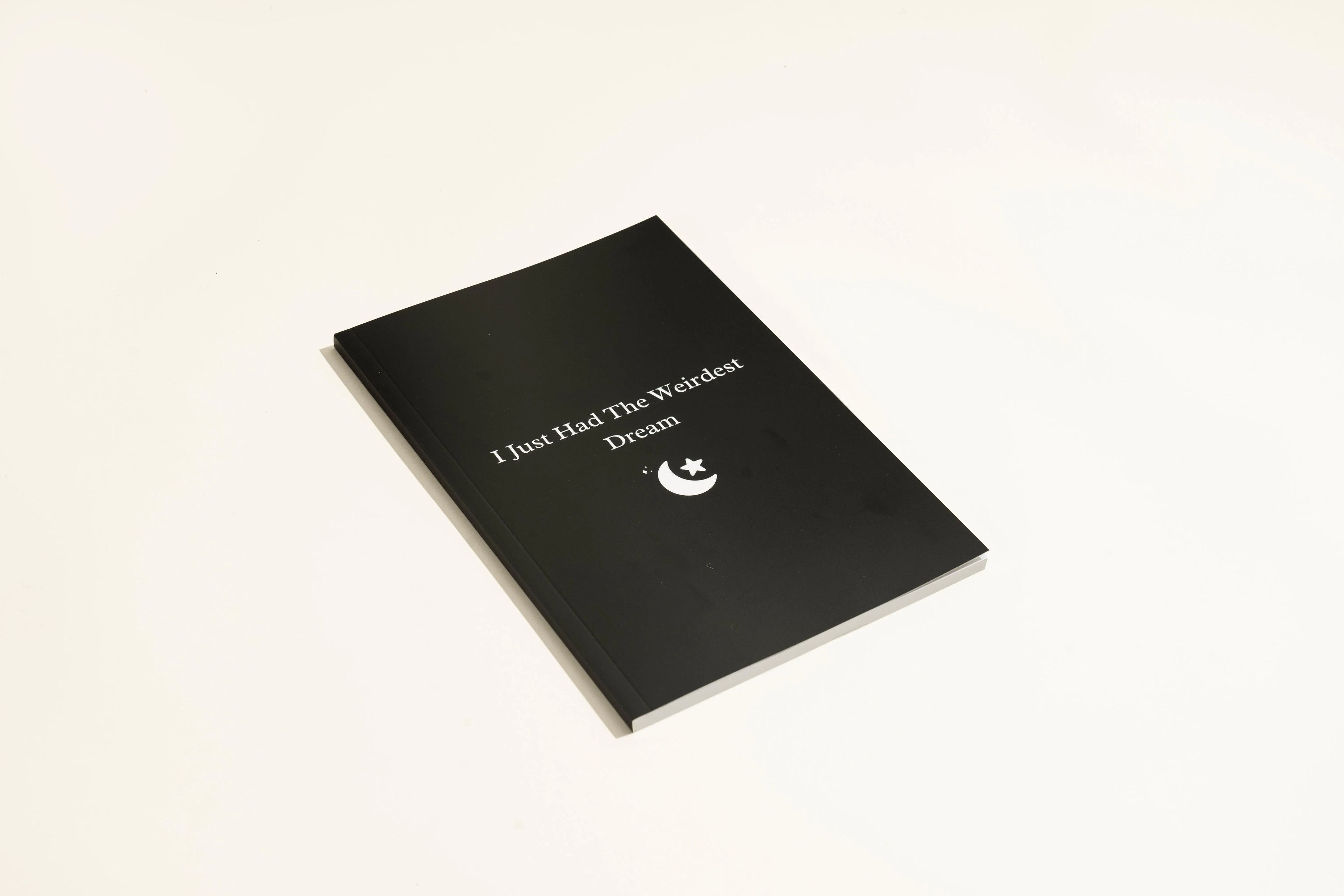Black A5 hardcover dream journal notebook with lined paper and a ribbon bookmark.
