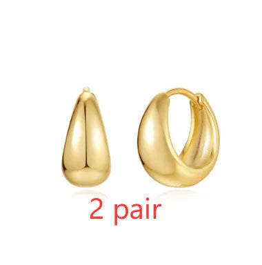 A pair of round, gold-toned brass diamond earclip earrings on a white background.