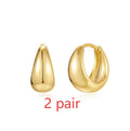 A pair of round, gold-toned brass diamond earclip earrings on a white background.