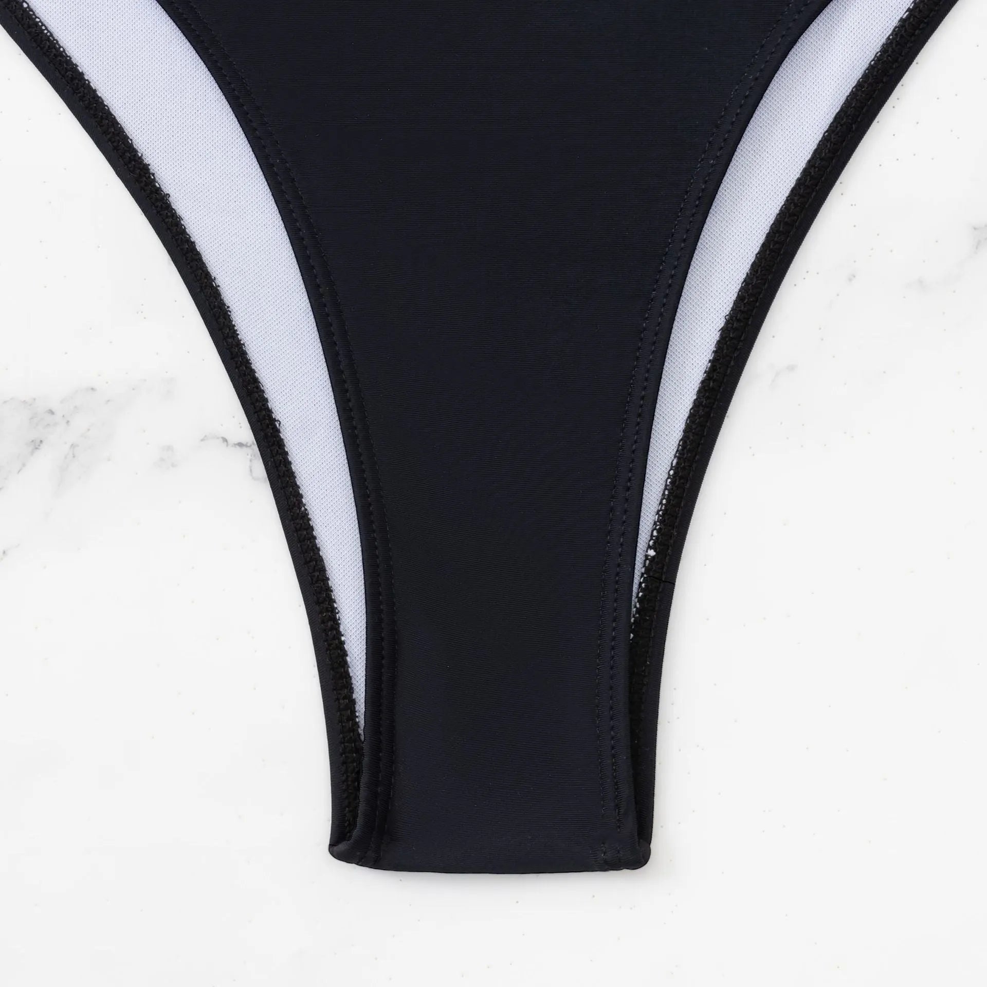 Black women's one-piece swimsuit with white contrast stitching and hollow cut-out design on a mannequin
