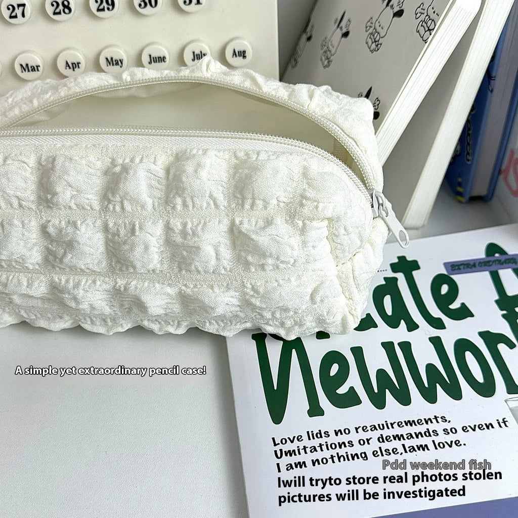 Beige fabric pencil case with a rounded cream puff design next to black version.