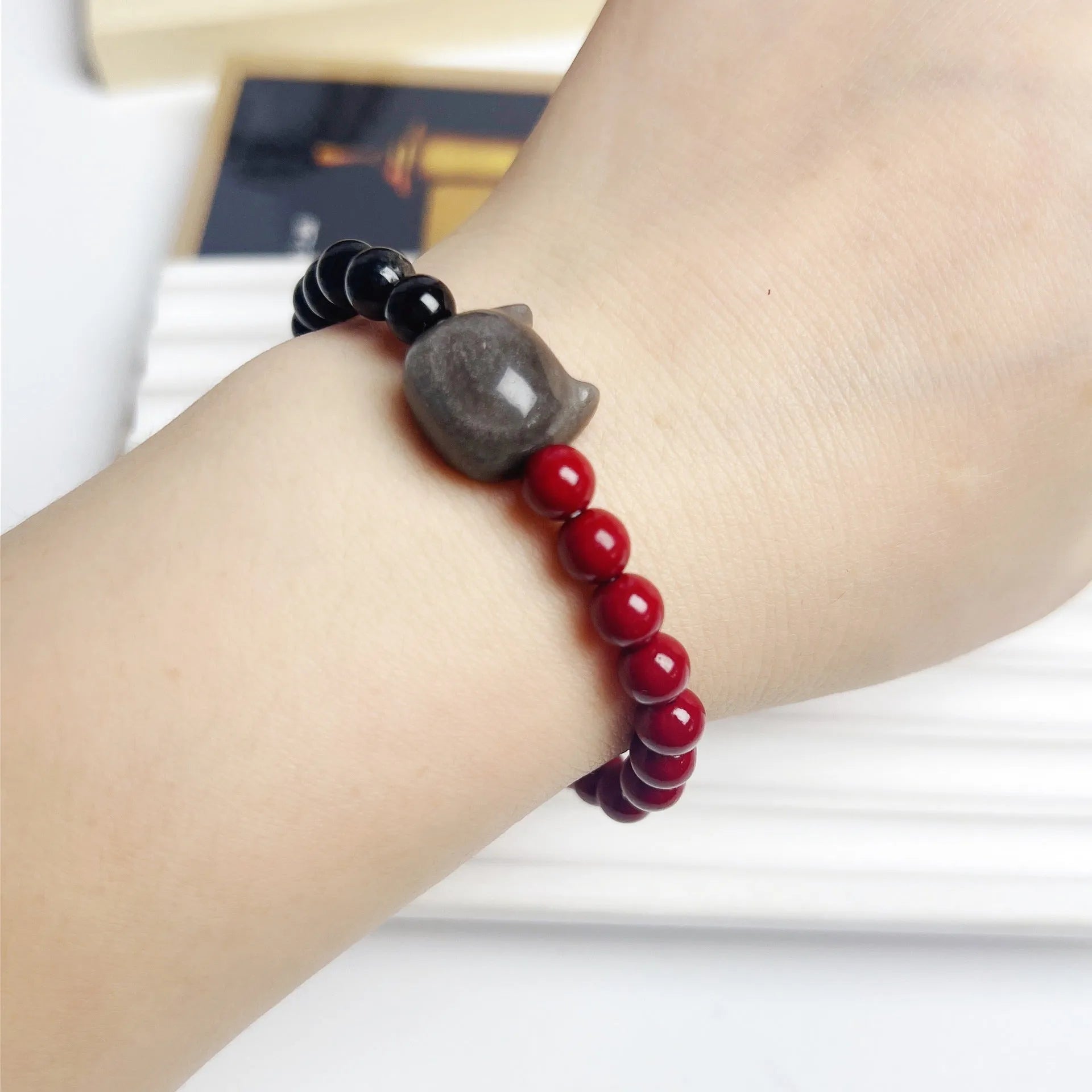 Handmade obsidian bead bracelet with a small cat charm on a cord.