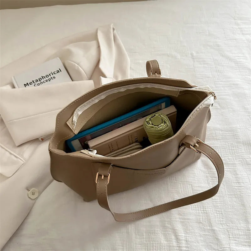 Women's black PU tote bag with shoulder straps showing internal mobile phone pocket