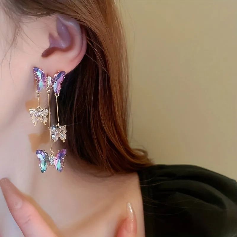 A pair of silver needle crystal flower and butterfly tassel earrings in a blue purple electroplated colour.