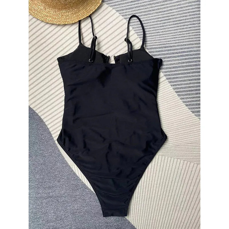 Black women's one-piece swimsuit on hanger showing solid colour design and contemporary cut