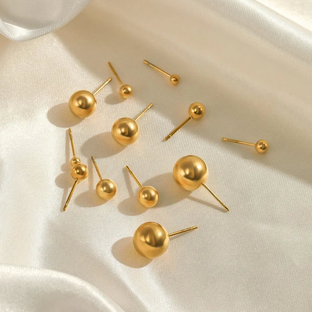 Simple stainless steel stud earrings with geometric sphere design in gold colour on white background