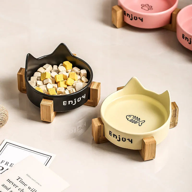 Porcelain cat bowl with cat ear handles in a wooden anti-tumble frame, showing paw print design.