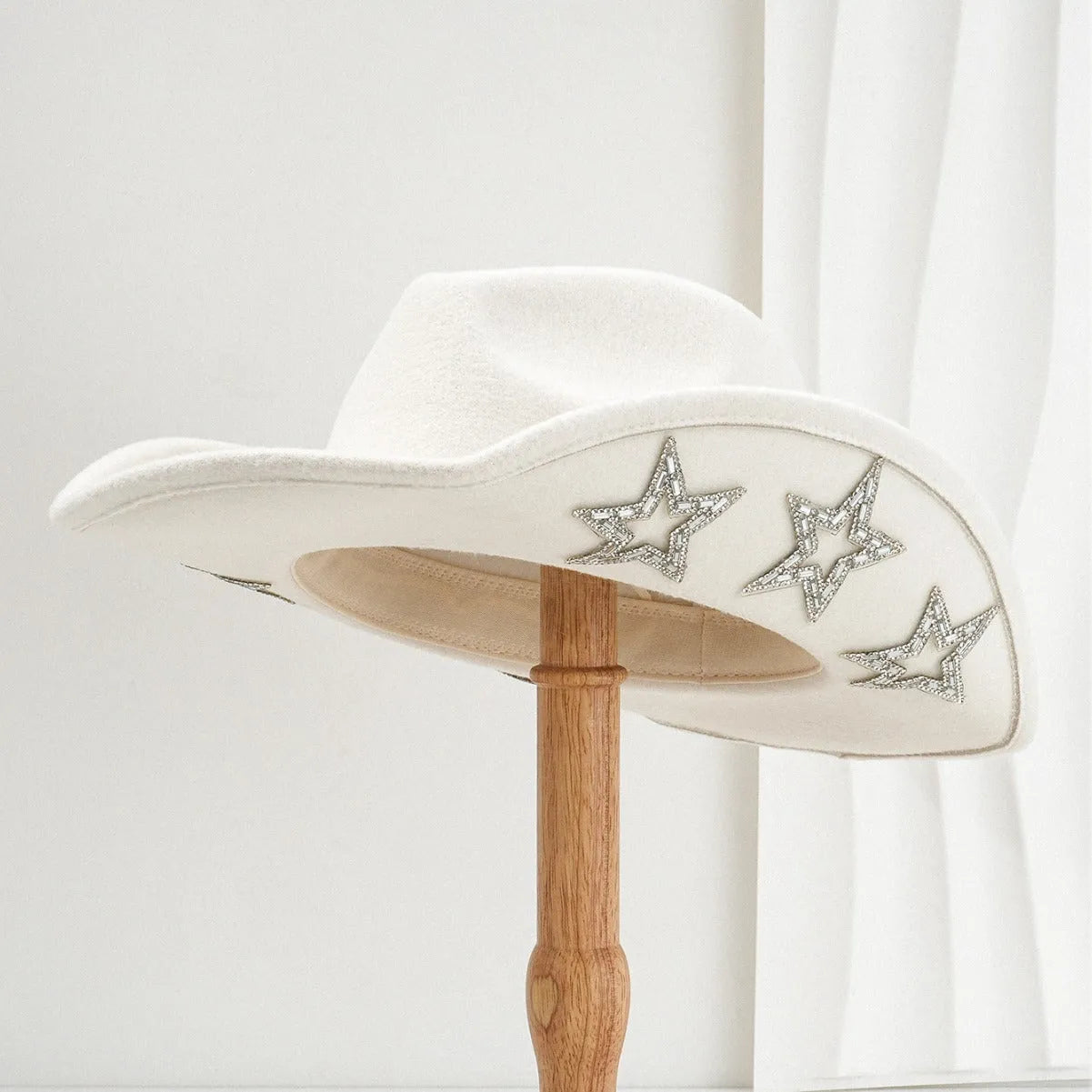 Beige polyester felt western-style top hat with a conical crown and a hexagonal star decoration on the front.