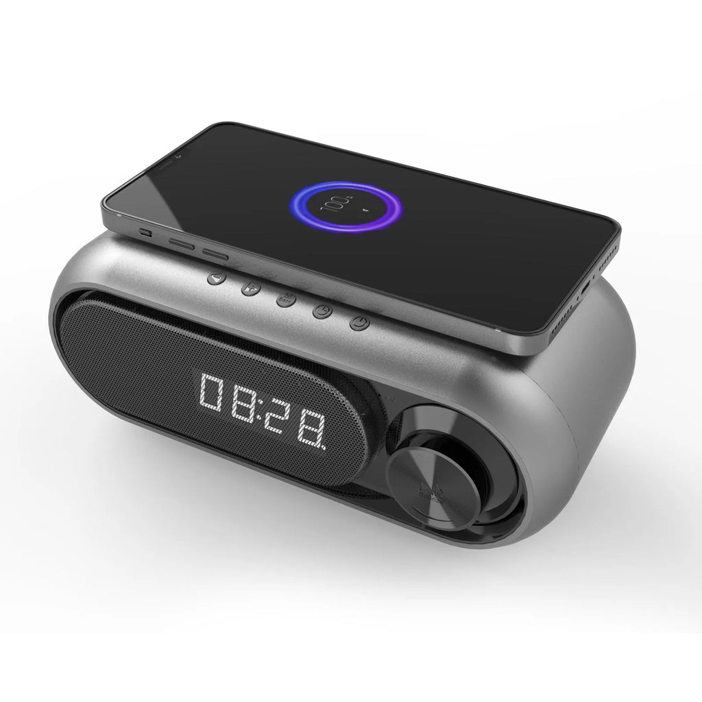 Space Grey wireless charging Bluetooth alarm clock speaker with LED display on a bedside table.