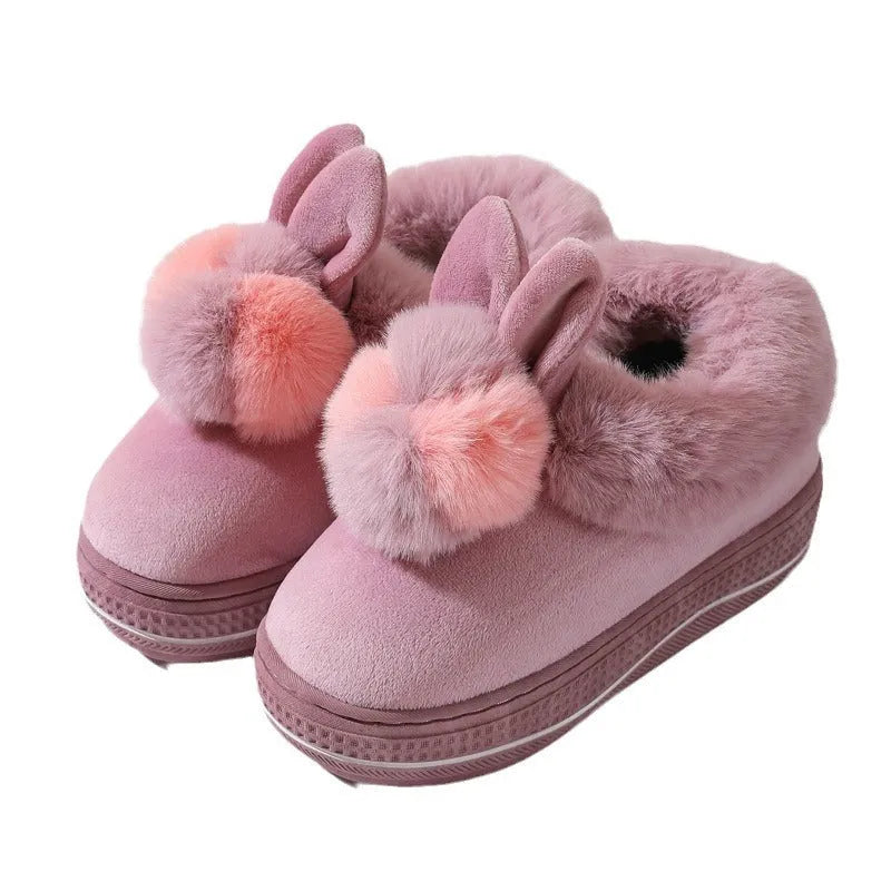 Grey plush high-heel winter slippers with a thick TPR sole on a wooden floor.