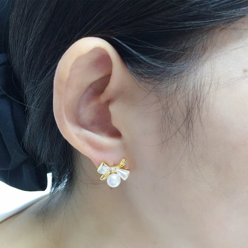Two-tone bow pearl stud earrings in white or gray with flat circle shape