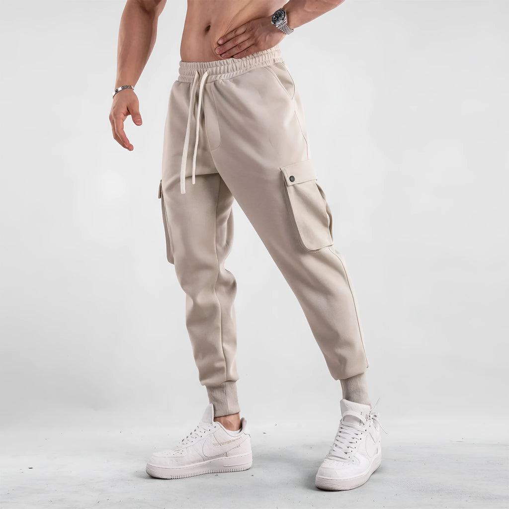 Man wearing loose light grey cotton sports trousers with ankle ties and multiple pockets.