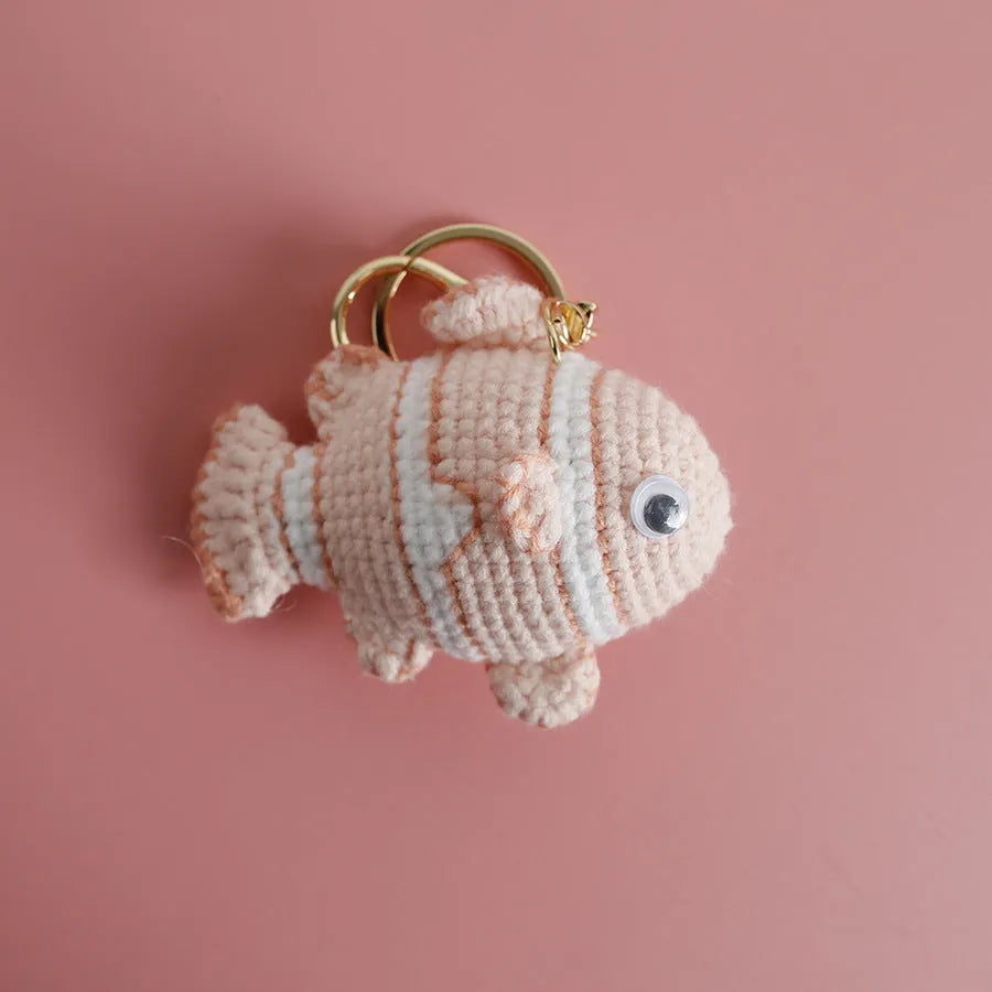 Crocheted wool fish keychain in cartoon ugly fish doll style with key ring, shown in orange, blue or pink