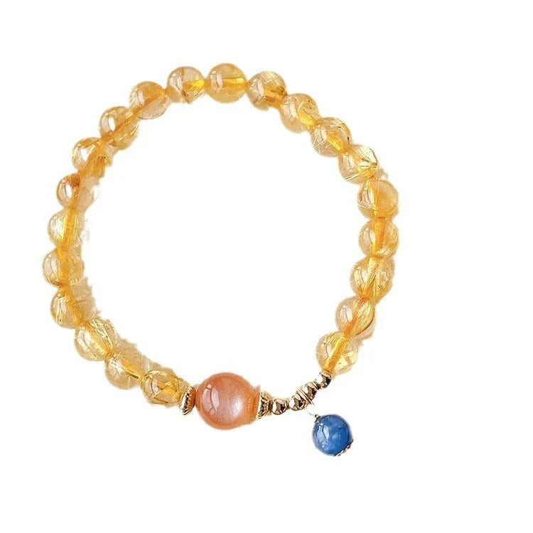 Gold rutilated quartz sunstone bracelet with diamond shapes and round beads on female wrist