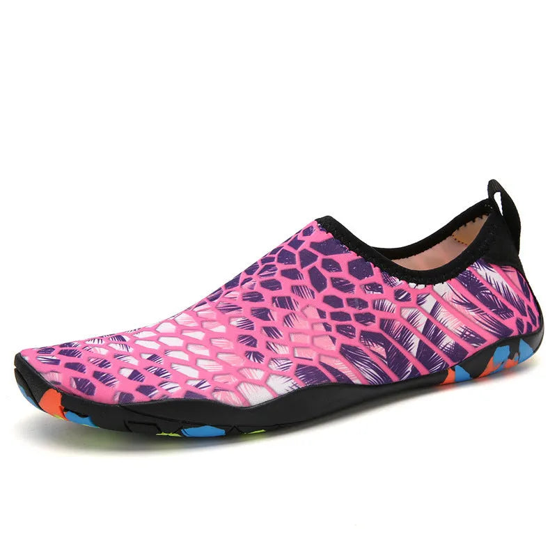 Blue Lycra beach wading shoes with decorative printing, shown on a sandy background